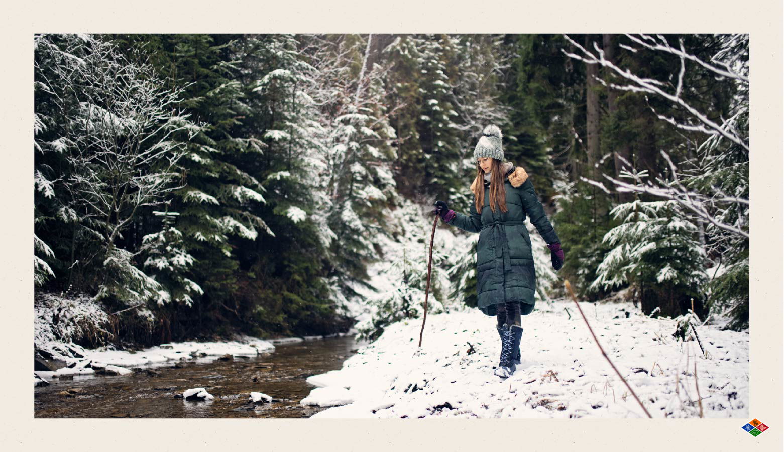 Hiker walking next to a creek in a snowy forest