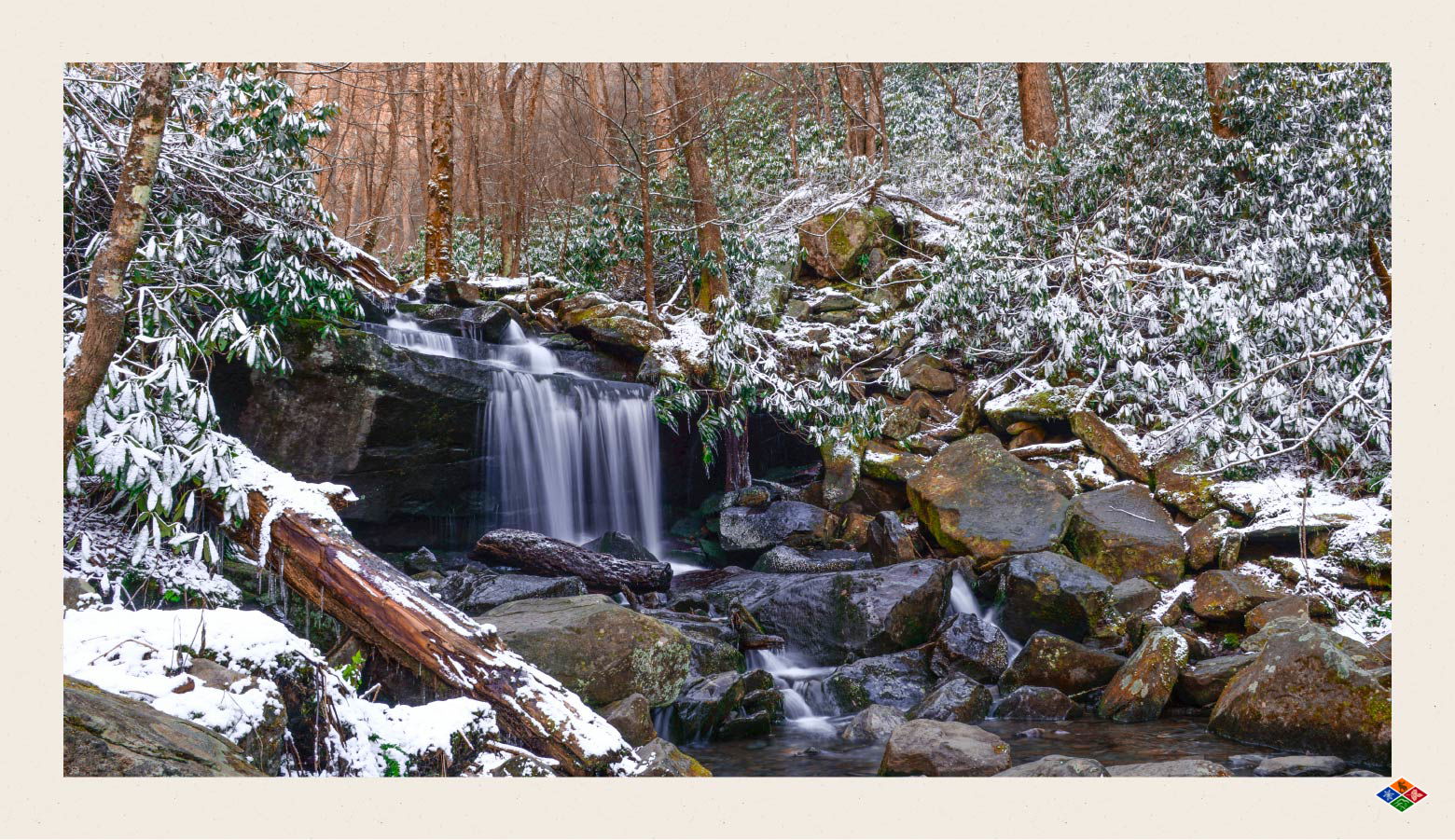 Waterfall surrounded by rocks and snowy tress