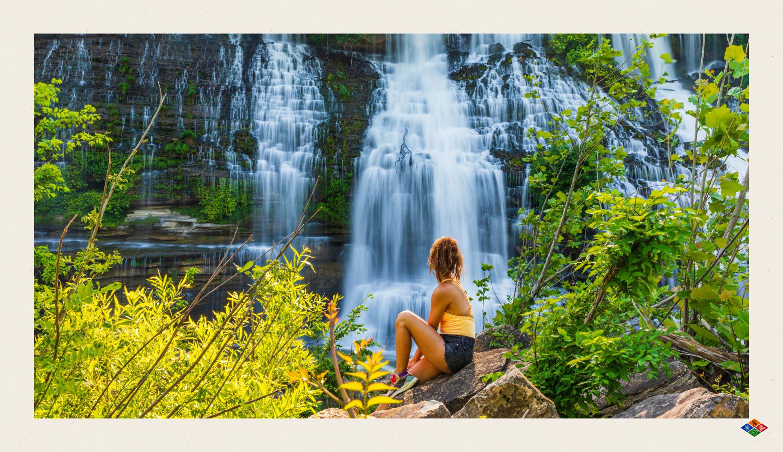 Woman sitting at the base of a Smoky Mountain waterfall in summer