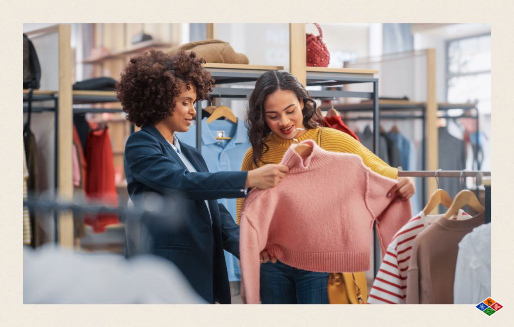 Two individuals shopping for clothing, holding up a pink sweater.