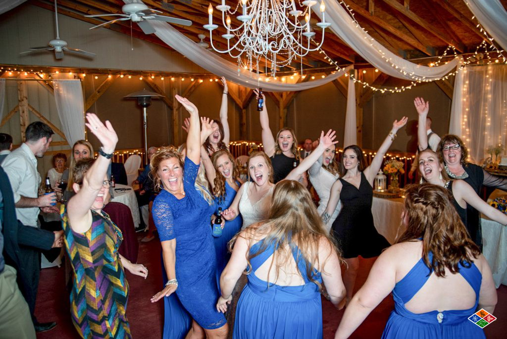 Wedding guests dancing with their arms in the air at a Bluff Mountain Inn barn reception