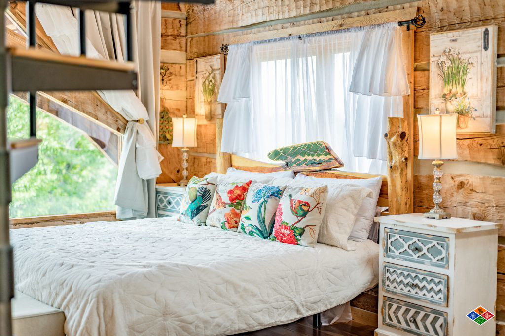 Bedroom at Cielito Lindo with a king bed, sheer curtains and a tall window looking into the treetops