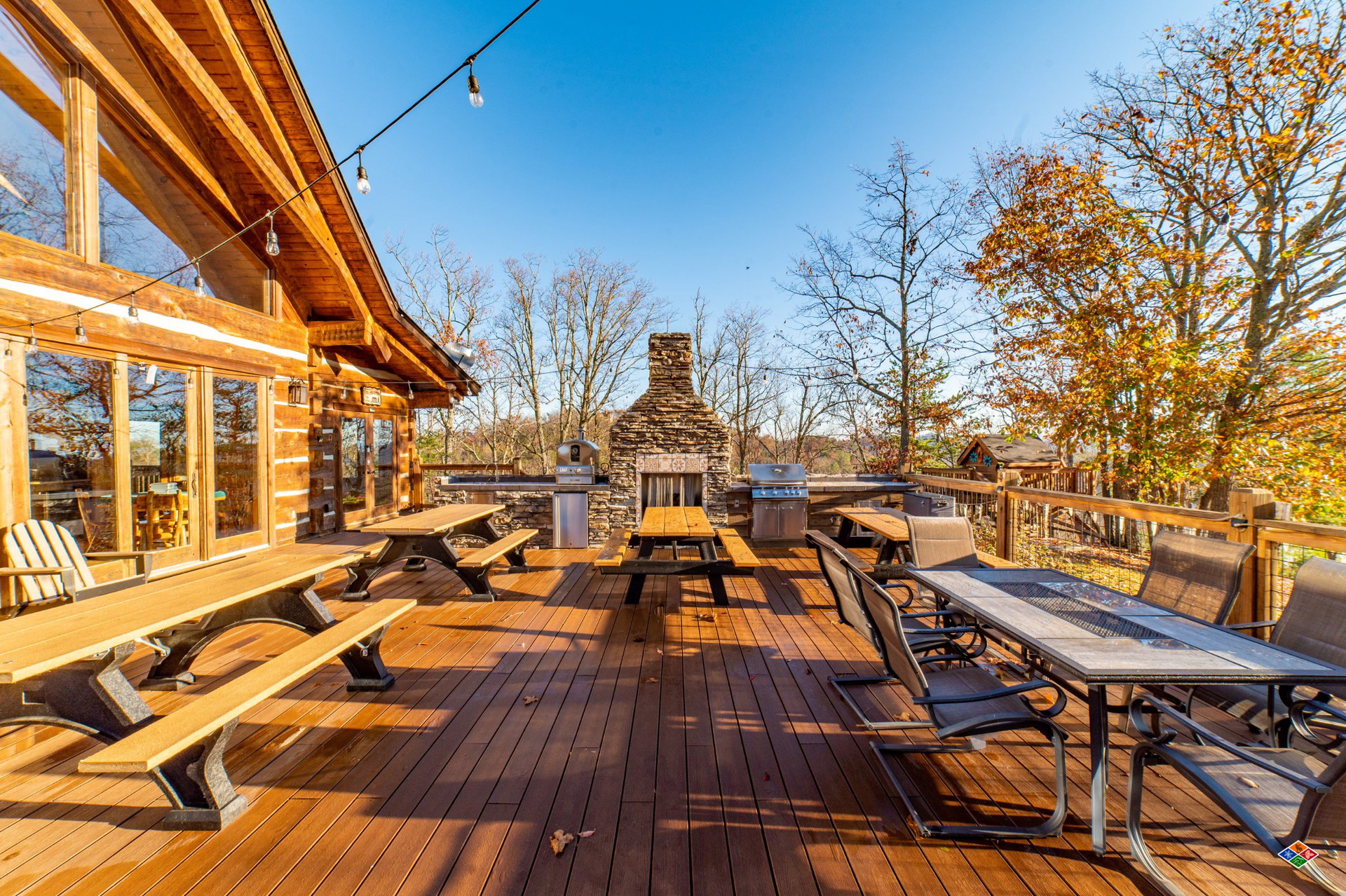 The expansive deck at Cielito Lindo with picnic tables, string lights and a stone outdoor fireplace
