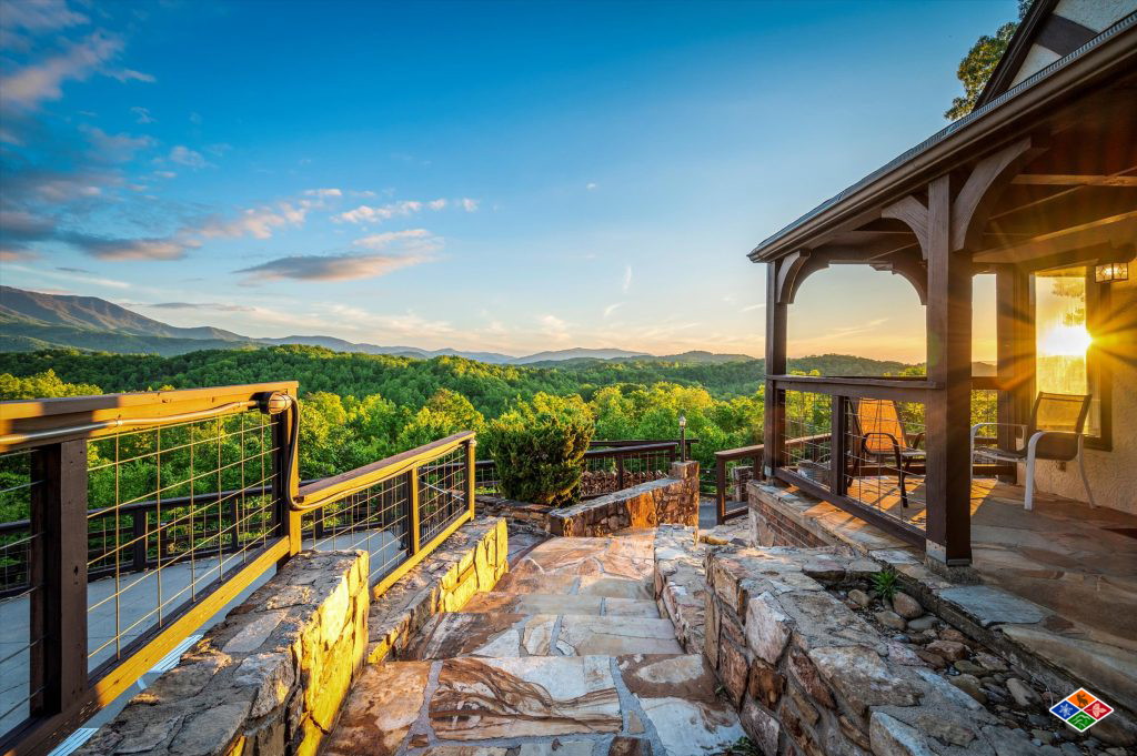 Stone steps and a covered porch at Mountain View Mansion glowing at sunset, with the Smoky Mountains stretching beyond